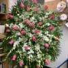 A standing spray consisting of medium pink roses, white dendrobium orchids and