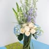 Unique arrangement with white and blue flowers arranged in a clear vase.