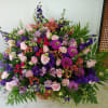 A wicker basket filled with purple Larkspur and lisianthus, Pink roses and