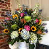 Tall and showy funeral display filled with bright summer colors. Light Blue