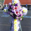 Floral cross made with chrysanthemums and decorated with a spray of roses
