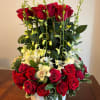 This arrangement includes red and hot pink roses, dendrobium orchids, Cabbages