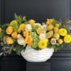 Yellow and green arrangement in white vase. Lemons are added for fresh