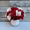 White cylinder with a pink band with two dozen red roses with