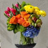 Flat bowl composed of bright vibrant blooms such as hydrangeas, roses, ranunculus