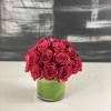 About two dozen premium roses in a cylinder vase with greenery cover