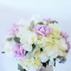 Silver ceramic cup filled with a mixture of roses, hydrangea, and dusty