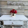 Glittered red roses with greenery and pink waxflower in a white and