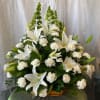 This light brown basket is filled with white carnations and lilies. The