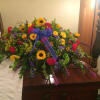 casket piece with sunflowers, red carnations blue delphinium, liatris and solidago