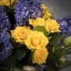 Summer Solstice features yellow spray Roses and purple Hyacinths, and seasonal flowers