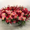 A stunning medley of red, pink, and peach roses with accents of