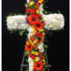 A sympathy cross with a body of white flowers and a colorful