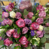 A mixture of purple roses, white roses, purple larkspur, lisianthus, and silver