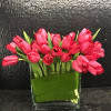 All red Dutch tulips wrapped with banana leaves in glass vase.
