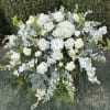 This casket spray is made with assorted white and soft yellow flowers.