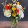 A mix of colorful dahlias, white hydrangeas, seed eucalyptus in a clear
