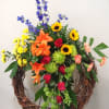 The grapevine wreath is enhanced with yellow sunflowers, green spider mums, yellow
