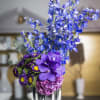 Beautiful hues of blue &amp; purple seasonal flowers in a round container-