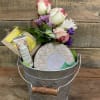 A decorative planting container filled with a large Voluspa candle, bar of