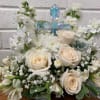 A crystal cross surrounded by roses and carnations.