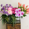 Modern arrangement in clear vase. Flowers may include but not limit to