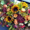 Includes Sunflower,  Roses,  mums,  Carnations,  Poms, and Solidagos.