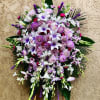 Beautiful standing spray arrangement with mixed purples, whites, and greens. Featuring lilies
