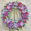 Beautiful violet and red standing funeral spray flowers featuring mums, orchids, daises