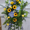 Traditional Standing spray of golden sunflowers, yellow roses, blue delphinium, bells of