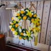 Yellow and White Lilies and Roses in a wreath of variegated greenery