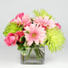 Pink roses and gerbera daisies in a clear square vase