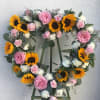 Pink roses, white carnations, and sunflowers on an 18&quot; open heart. pictured