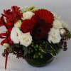 A vase of red gerbera daisies, red carnations, alstroemerias, white lisianthus, roses
