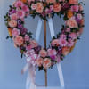 An open heart sympathy arrangement filled with pink chrysanthemums. A side accent