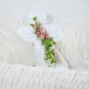 A satin cross pillow enhanced with a touch of flowers. Approximately 6&quot;W