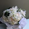 A petite bouquet of white hydrangea, roses and cymbidium orchid blooms in