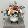 Modern white ceramic with wood stand is filled with hydrangeas, roses, thistle