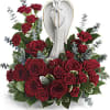 An angel figurine surrounded by red roses, spray roses and greenery.
Approx. 15&quot;