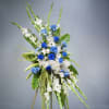 Vibrant blue roses and classic white gladiolus fill this elegant standing arrangement