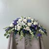 A dark blue and white casket spray featuring lilies, roses, hydrangeas, iris