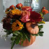 Orange pumpkin container with bright seasonal flowers.
