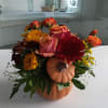 Orange pumpkin container with bright seasonal flowers.
