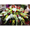A beautiful casket spray with red roses and mixed yellow and white