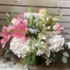 Modern arrangement with lilies, hydrangeas, tulips, roses arranged in a cylinder vase.