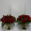 An elegant arrangement of winter greens, red roses and a white taper