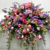 Casket spray of shades of pinks and lavender roses, snap dragons and