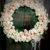 A white and blush pink floral wreath, with it&#039;s soft
and subtle petals