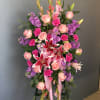 This standing spray consists of stargazer lilies, soft pink roses, purple hyacinth