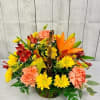 A basket arrangement of fall flowers such as daisies, carnations, lilies and